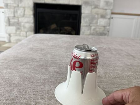 A Diet Dr Pepper can in a white Steadi on a taupe blanket, a stone fireplace behind.