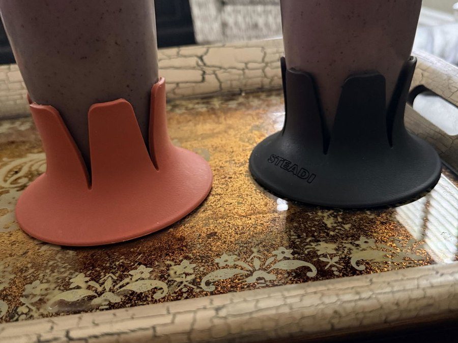Two Steadis, one coral and one black, each holding a berry smoothie on a gold tray.